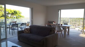 A living room with a sofa, a dining table with chairs, and a balcony with a view. - PRETTY VILLA, independent, close to the beach, the mountains, the shops! (VENTISERI)