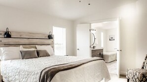A bedroom with a large bed, bedside tables, a nightstand, and a wardrobe. - "Trail Leader" Newly Remodeled Single Family Home (Moab)