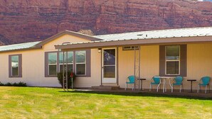 A single-story building with a flat roof, a front porch with four chairs, and a large window. - "Trail Leader" Newly Remodeled Single Family Home (Moab)