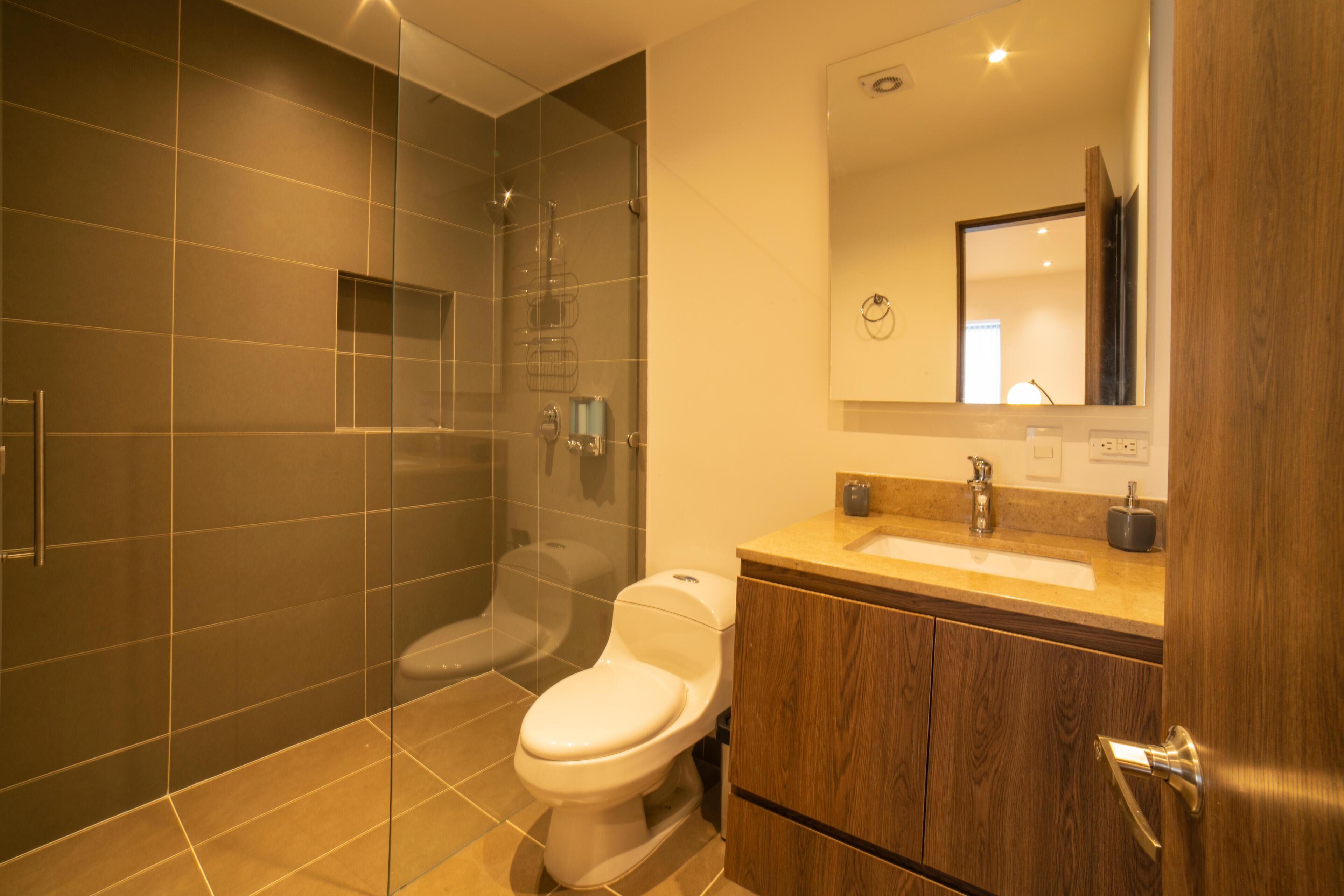 A modern bathroom with a glass-enclosed shower, a wooden vanity with a sink, and a toilet.