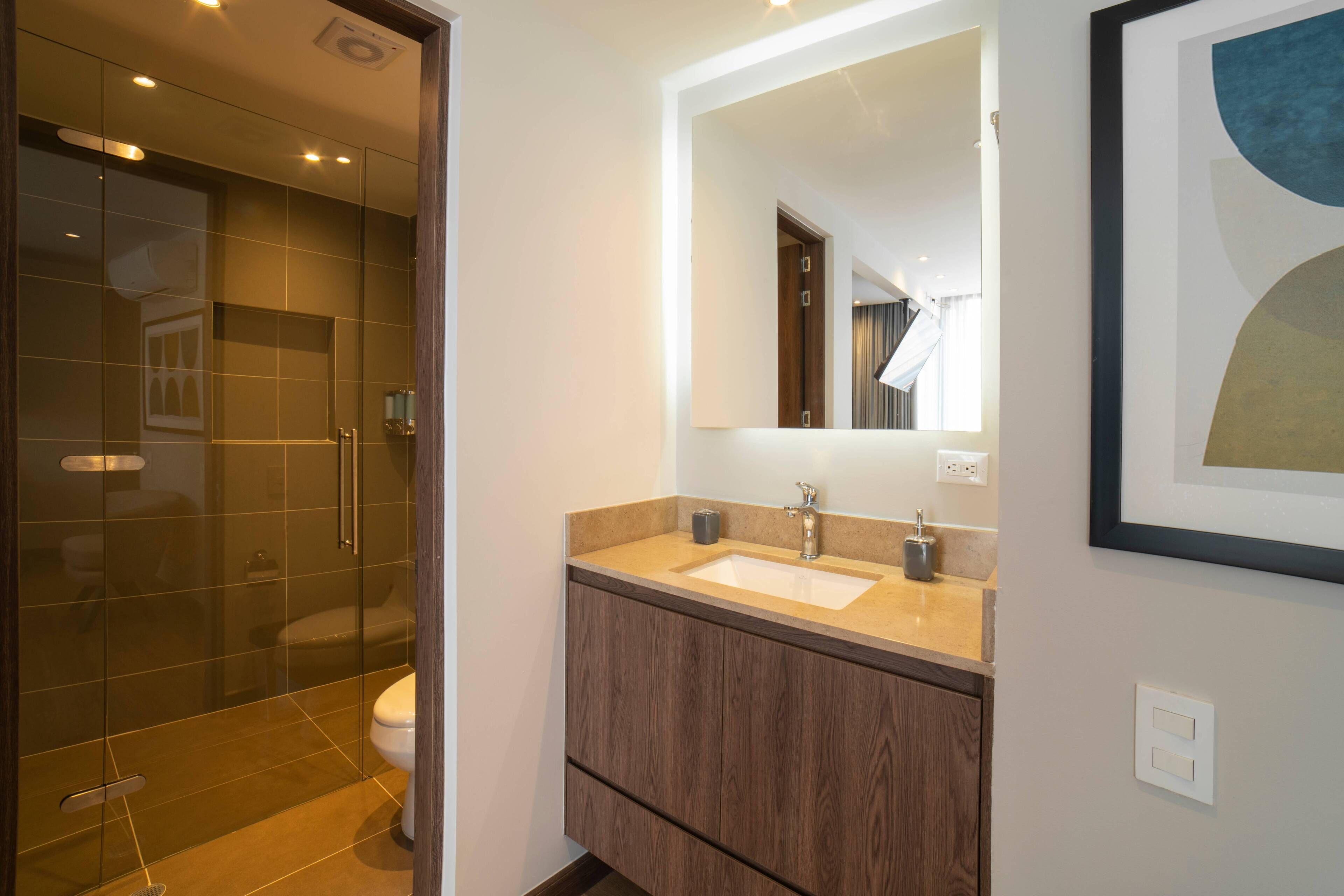 A modern bathroom with a glass shower enclosure, a double sink vanity, and a large mirror.