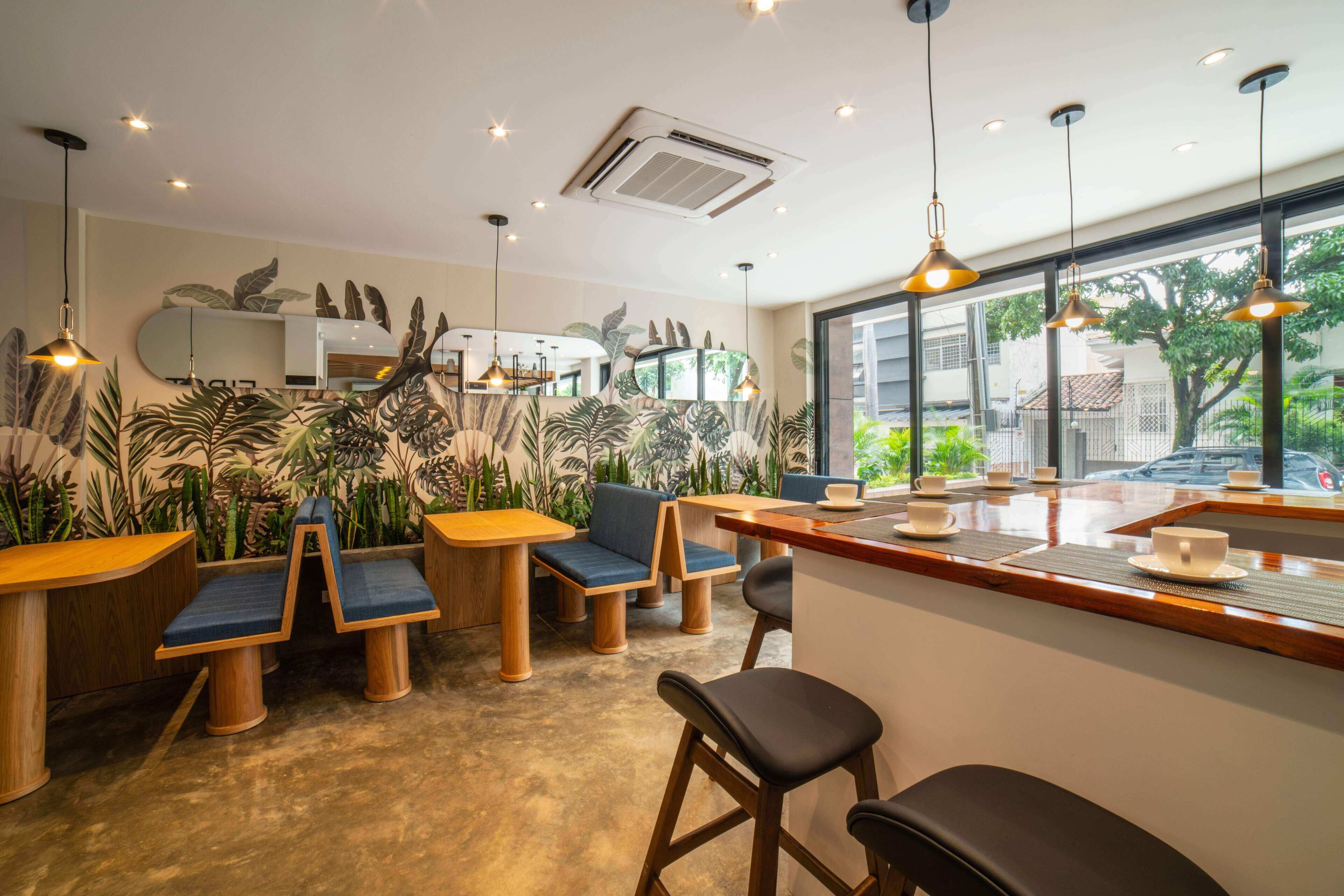 Een modern café met houten meubels, grote ramen en binnenplanten.