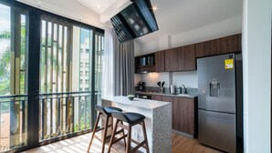 A modern kitchen with a large island, stainless steel appliances, and a view of greenery outside.