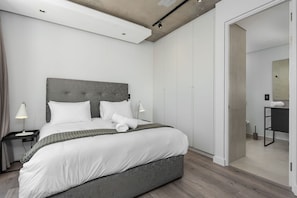 A modern bedroom with a large bed, bedside tables, and a walk-in closet. - The Signature 413 (Cape Town)