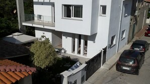 A modern two-story building with a balcony, a small garden, and parked cars. - La Fenice Budoni (Budoni)