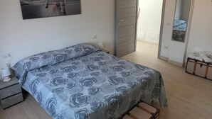 A bedroom with a bed, a painting, a wardrobe, and a suitcase. - La Fenice Budoni (Budoni)