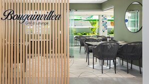 Moderni sisustus, jossa on puinen sermi, ja sermissä näkyy teksti ”Bougainvillea Grill & Lounge”.