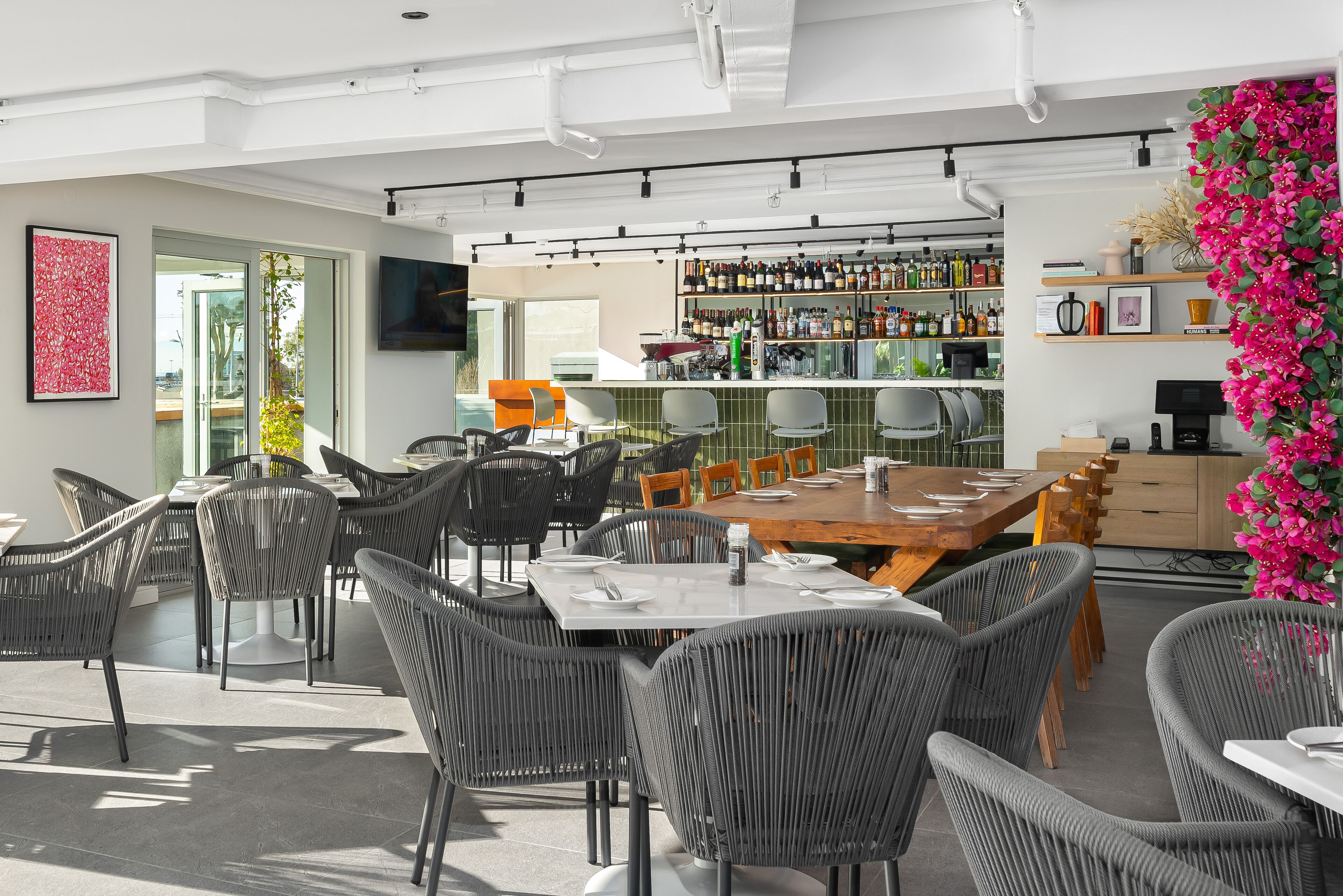 Un restaurante moderno con zona de bar, mesas y vistas al exterior.