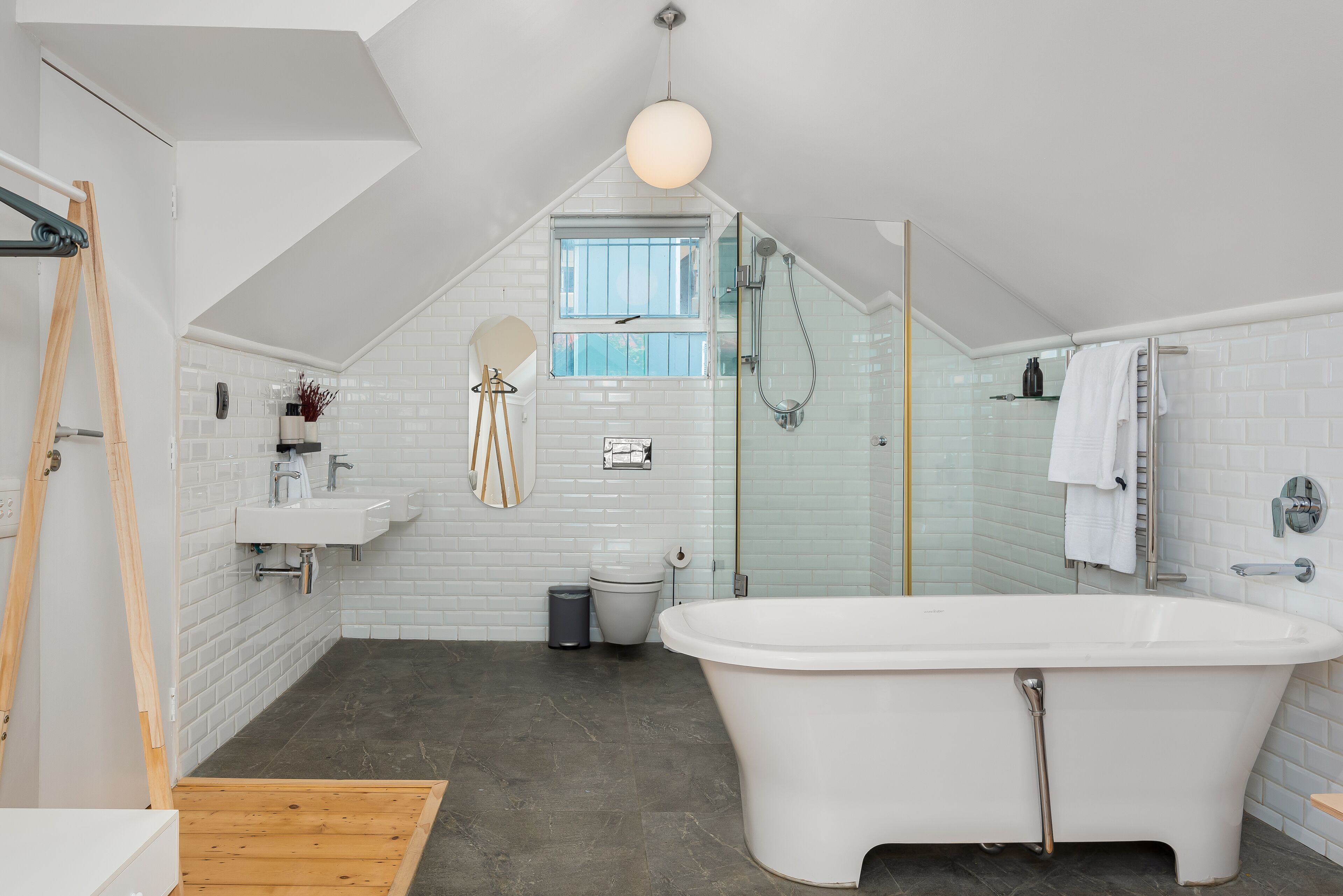Un bagno moderno con una vasca freestanding, una doccia con pareti in vetro e un rivestimento in piastrelle bianche.