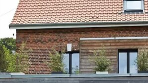 Ein modernes Haus mit Swimmingpool, Sitzgelegenheiten im Freien und einer Ziegel-Fassade.