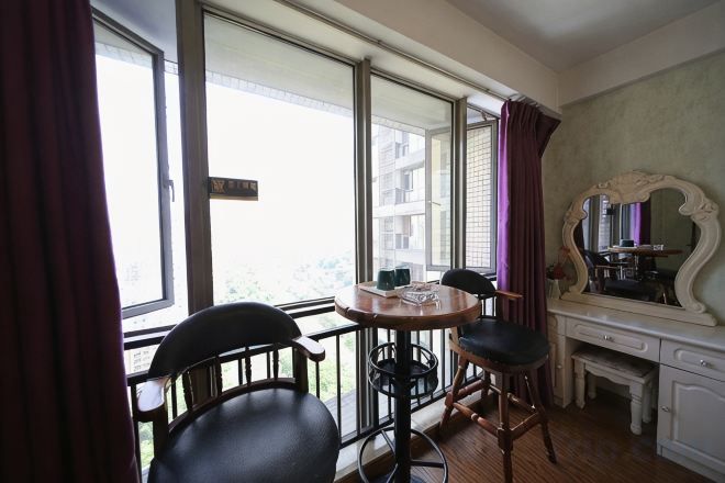 Una habitación con balcón, una mesa de comedor con sillas, un espejo y un pequeño escritorio.