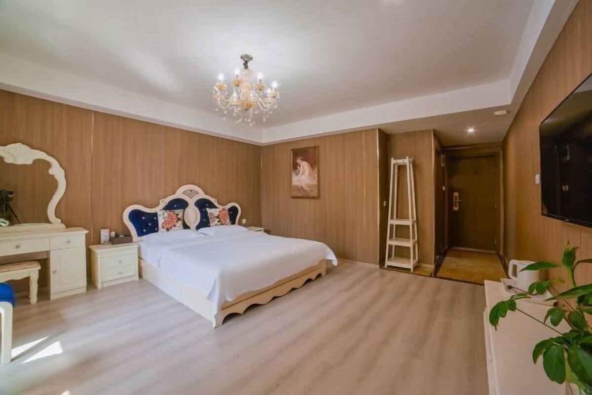 Un dormitorio con cama, cómoda, espejo, candelabro y televisor.