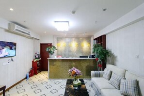 A hotel lobby with a reception desk, a sofa, a coffee table with flowers, and a TV on the wall. - Ziyuan Chuangyi Boutique Hotel Chongqing Ranjiaba (Chongqing)