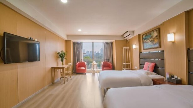 Habitación de hotel con dos camas, televisión, una mesita con sillas, ventana con vistas y equipo de aire acondicionado.