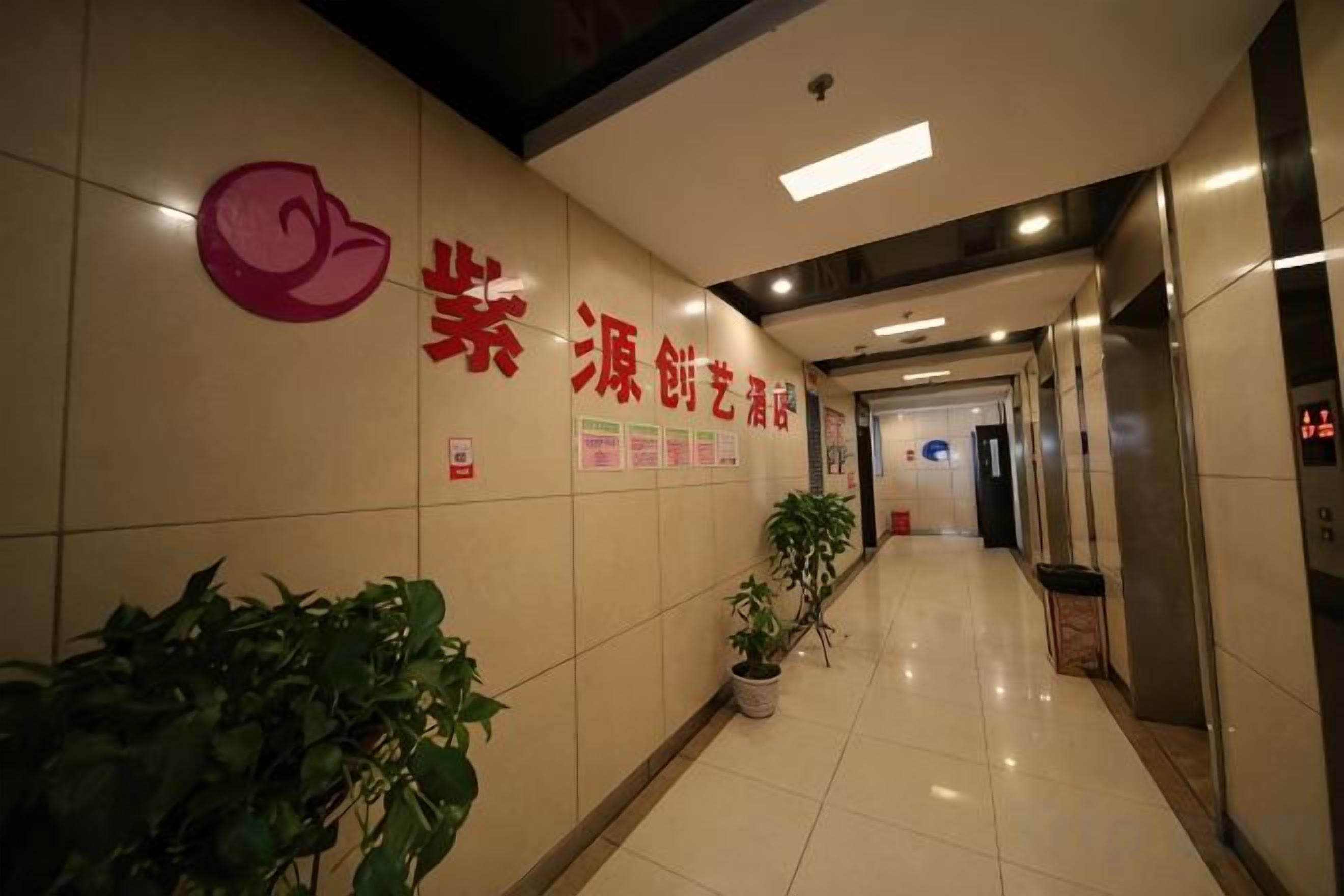A hallway with a reception desk, potted plants, and a sign with Chinese characters.