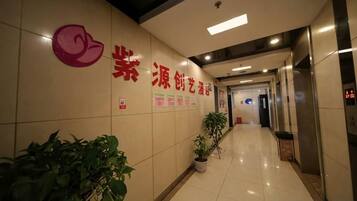 A hallway with a reception desk, potted plants, and a sign with Chinese characters.