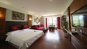 Una habitación de hotel con una cama grande, un sofá, una mesa de comedor y un televisor.