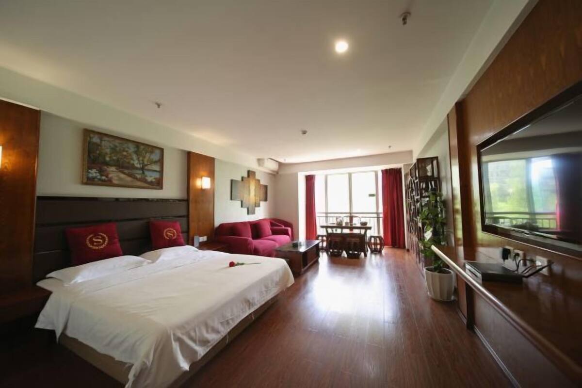 Una habitación de hotel con una cama grande, un sofá, una mesa de comedor y un televisor.