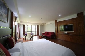 Ett hotellrum med en stor säng, en röd soffa, en tv och en balkong med utsikt.