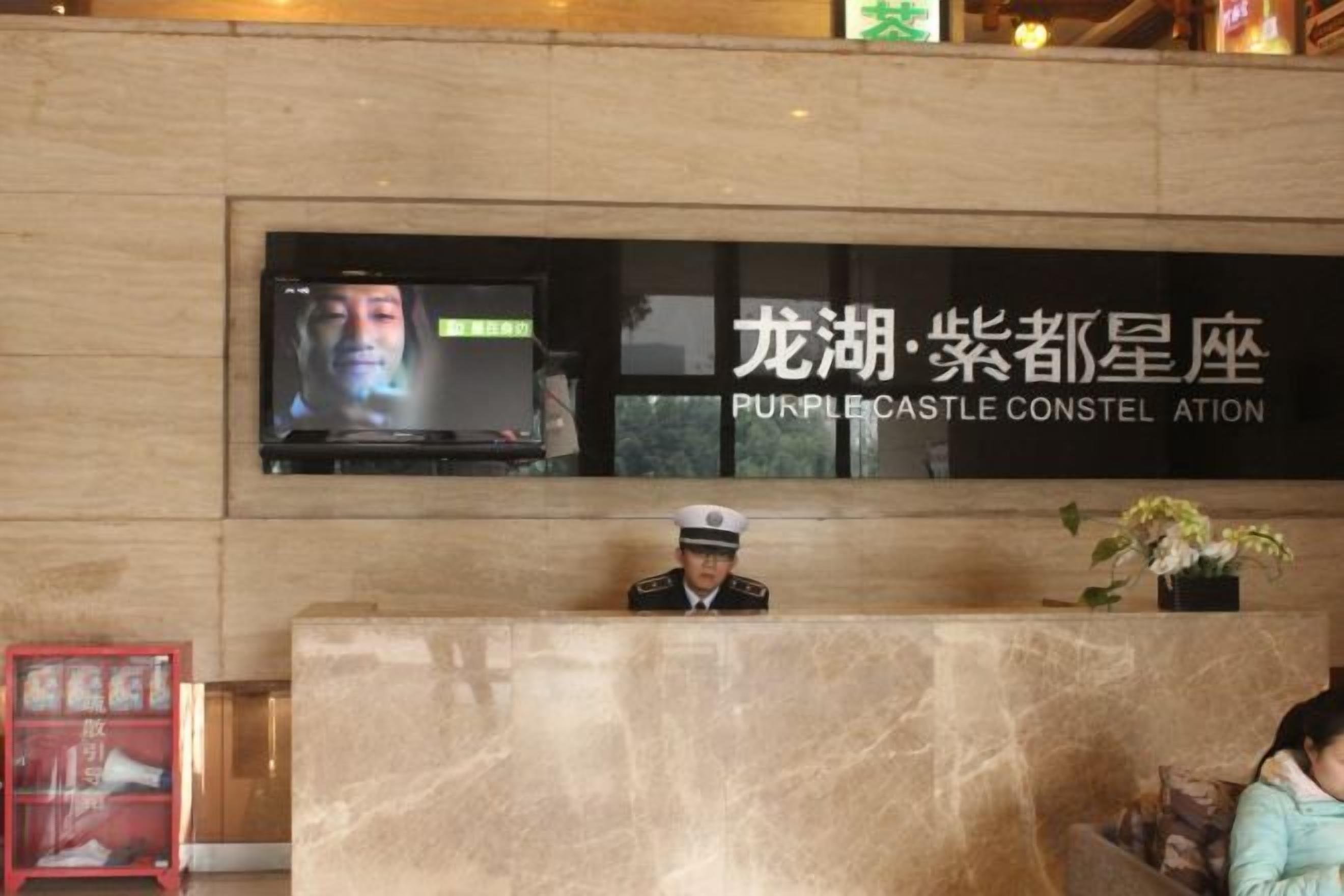 A reception desk with a television screen, a uniformed staff member, and a sign with Chinese characters.