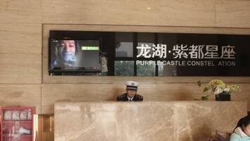 A reception desk with a television screen, a uniformed staff member, and a sign with Chinese characters.
