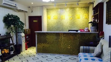 A reception area with a patterned wall, a reception desk, a sofa, and a potted plant.