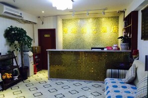 Ein Empfangsbereich mit Wandmuster, einer Rezeption, einer Couch und einer Zimmerpflanze.