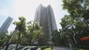 Un edificio alto de diseño moderno, rodeado de árboles y un sendero pavimentado.