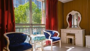 Una habitación con dos sillones tapizados en azul, un tocador blanco con espejo y una mesa con mantel azul.