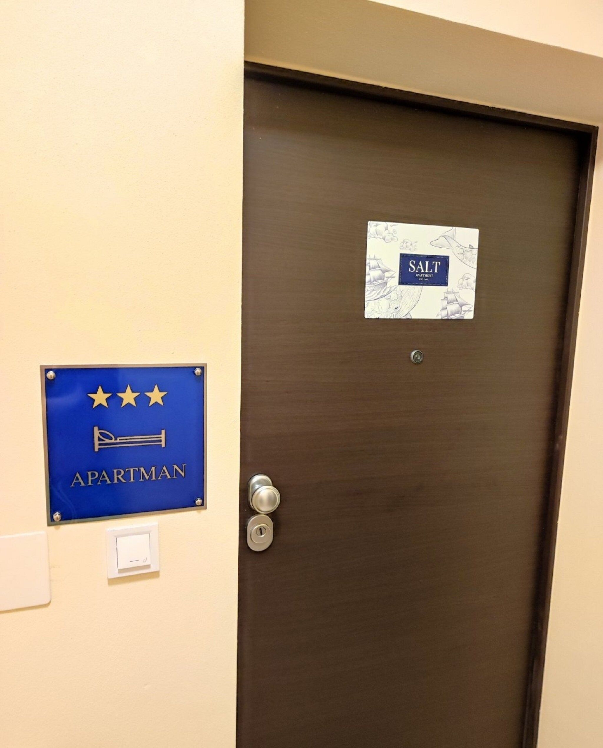 A door with a sign indicating 'APARTMAN' and another sign with 'SALT APARTMENTS'.