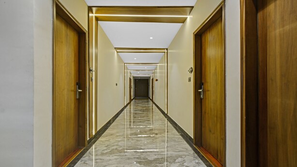 Un pasillo con puertas de madera, suelo de mármol e iluminación empotrada.