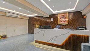 Zona de recepción de hotel con mostrador de mármol, pared revestida de paneles de madera y una obra de arte enmarcada sobre el mostrador.