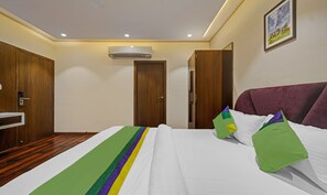 Habitació d'hotel amb llit, armari de fusta i aire condicionat.