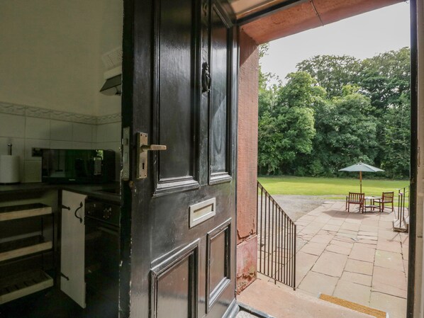 A kitchen with a dark wooden door, a microwave, and a sink. - The Residence (Cleator)