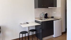Een kleine keuken met een spoelbak, een koffiezetapparaat en een koelkastje.