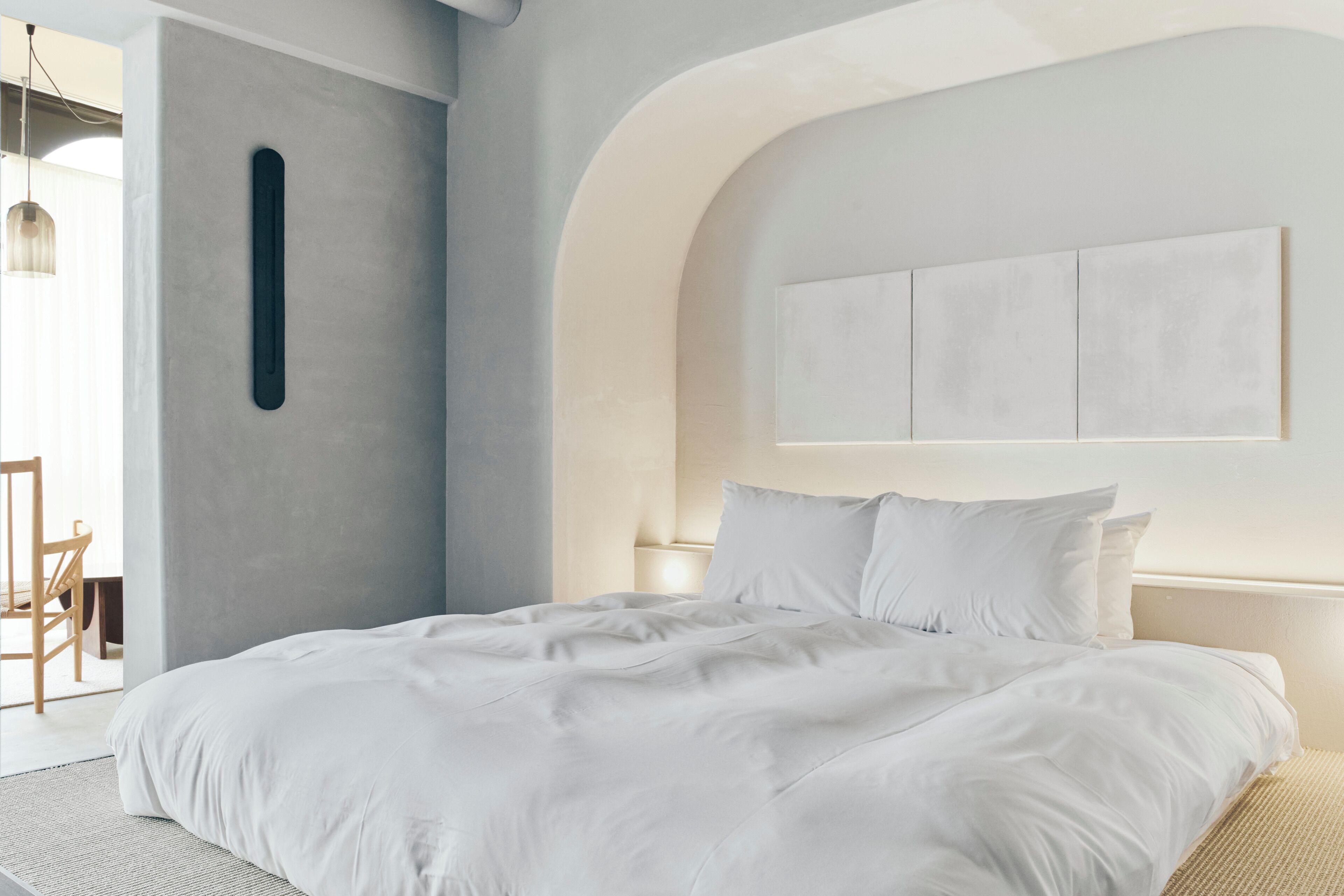 Een moderne slaapkamer met een groot bed, een wandlamp en een minimalistisch design.