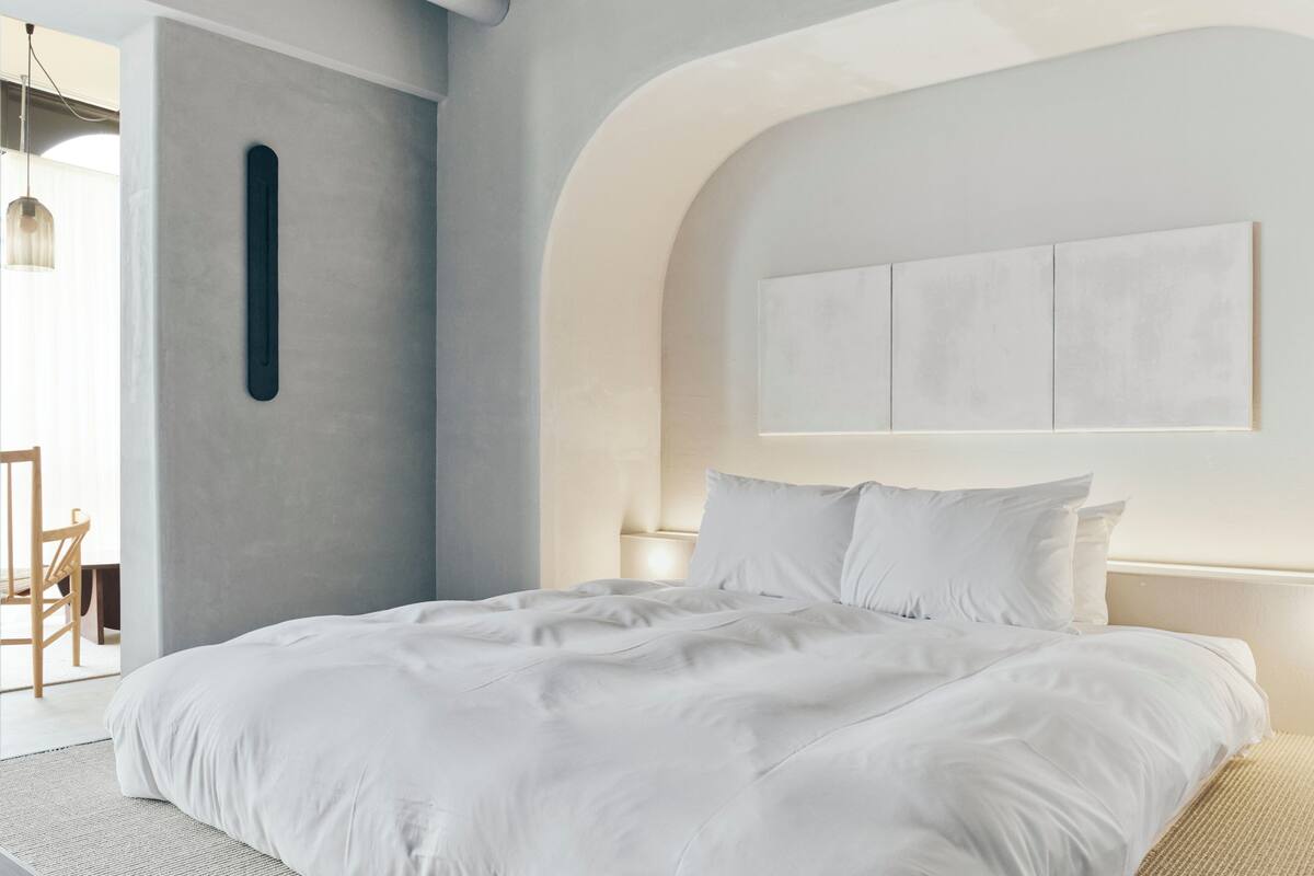 Un dormitorio moderno con una cama grande, una lámpara de pared y un diseño minimalista.