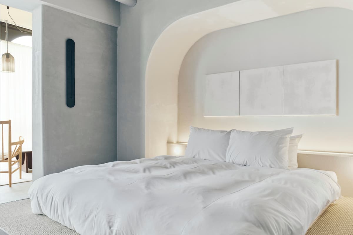 Un dormitorio moderno con una cama grande, una lámpara de pared y un diseño minimalista.