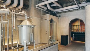 A modern industrial-style kitchen with stainless steel appliances, visible pipes, and a glass enclosure. - Korinkyo (Kanazawa)