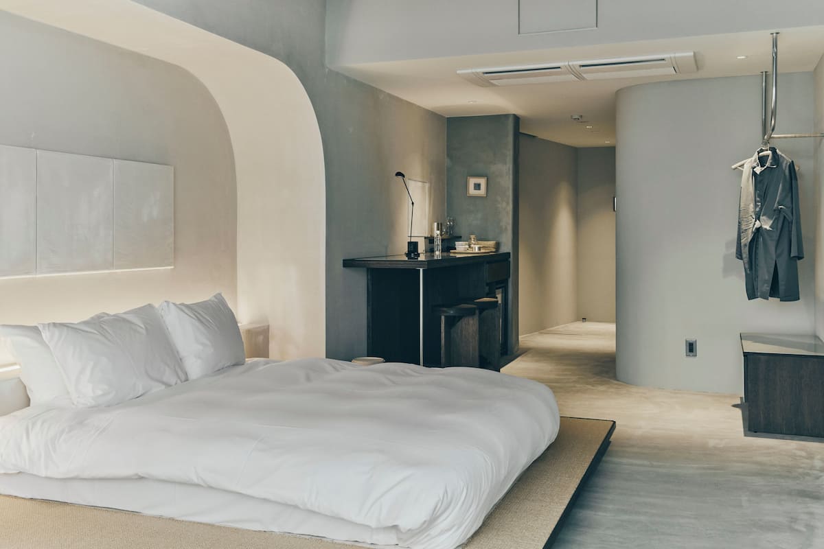 Un dormitorio moderno con una cama grande, un escritorio y un perchero.