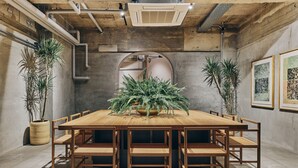 A conference room with a wooden table, chairs, potted plants, and framed artwork on the walls. - Korinkyo (Kanazawa)