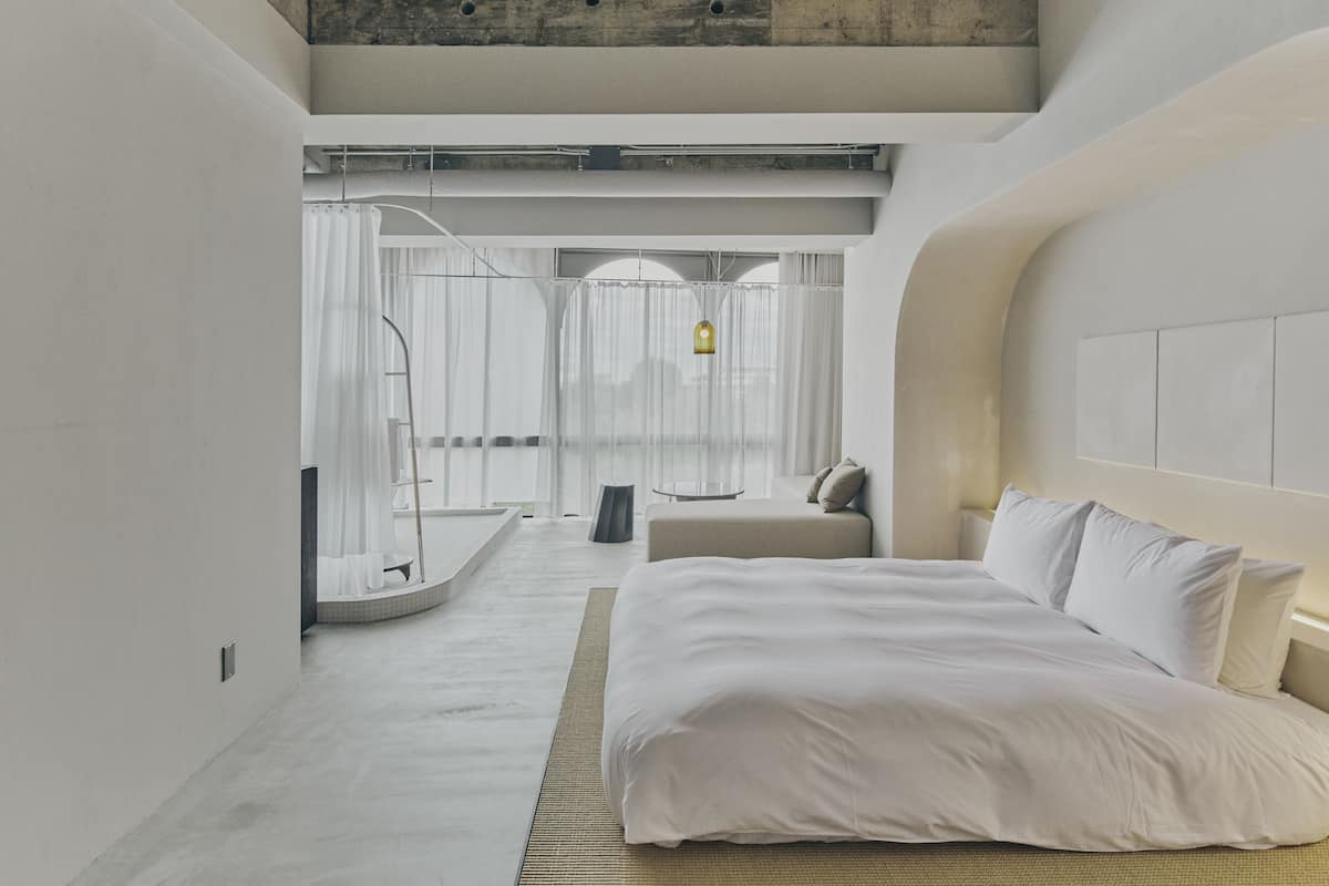Un dormitorio moderno con una cama grande, un área de descanso y una ducha con cortinas.