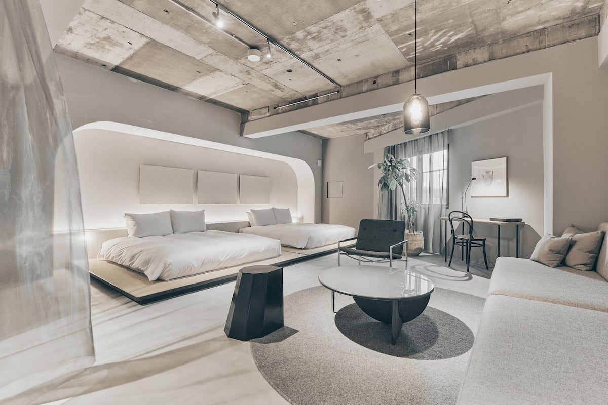Una habitación de hotel moderna con una cama grande, un sofá, una mesa de centro y un escritorio.