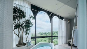 A modern bathroom with a freestanding bathtub, large windows, and a view of greenery. - Korinkyo (Kanazawa)