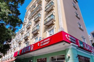 Un edificio de varios pisos con fachada roja y verde, que presenta un letrero con números de contacto.