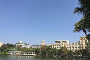 Un hotel frente al agua con un edificio grande, un lago y un muelle para barcos.