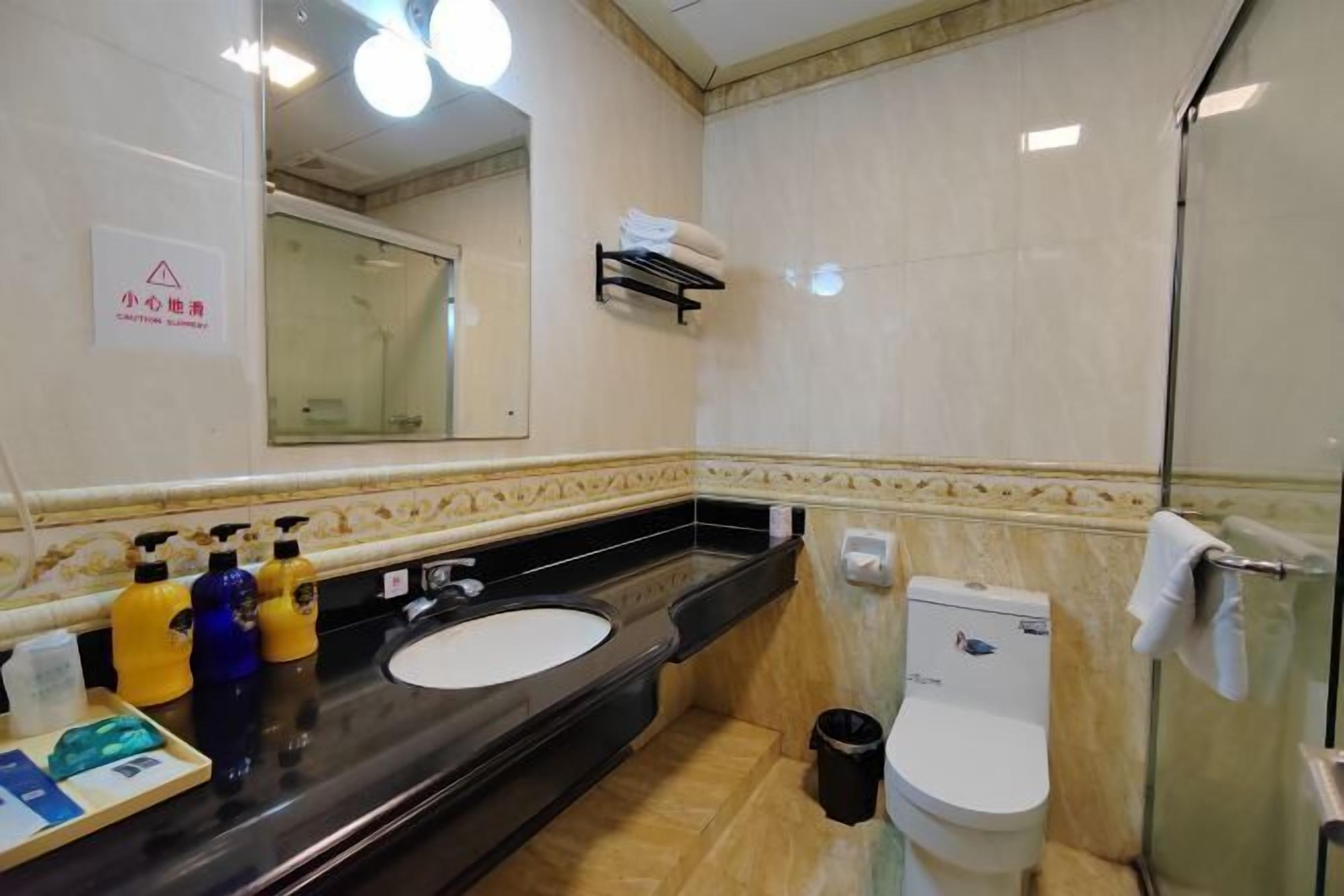 Un baño con un lavamanos negro, un inodoro blanco y una cabina de ducha de vidrio.