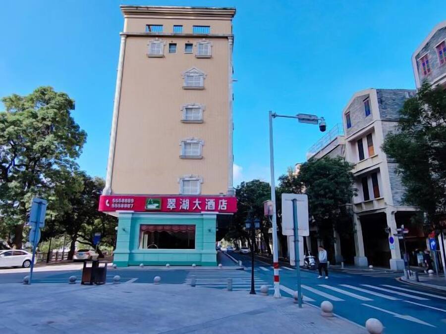 Un hotel con un cartel vertical llamativo, una escalera que lleva a la entrada y un cielo azul despejado.