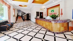 Et hotel lobby med en receptionsdisk, en trappe og et flisegulv.