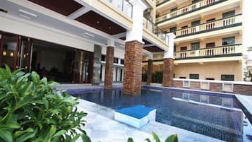 A hotel with a central swimming pool, multiple balconies, and a modern architectural design.